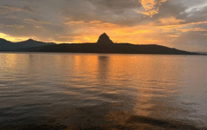 Tranquil lake in Lonavala surrounded by green hills during a colorful sunset