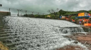 Bhushi Dam in Lonavala with flowing water and surrounding green hills on a sunny day